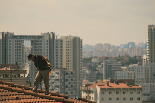 Construction worker on a rooftop in İstanbul with city skyline in the background.